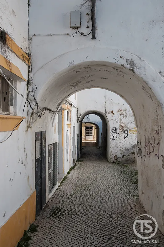 Arco branco no centro histórico de Lagos com calçada portuguesa e passagem estreita