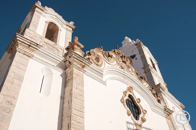 Fachada barroca de igreja em Lagos com torres sineiras e frontão decorado
