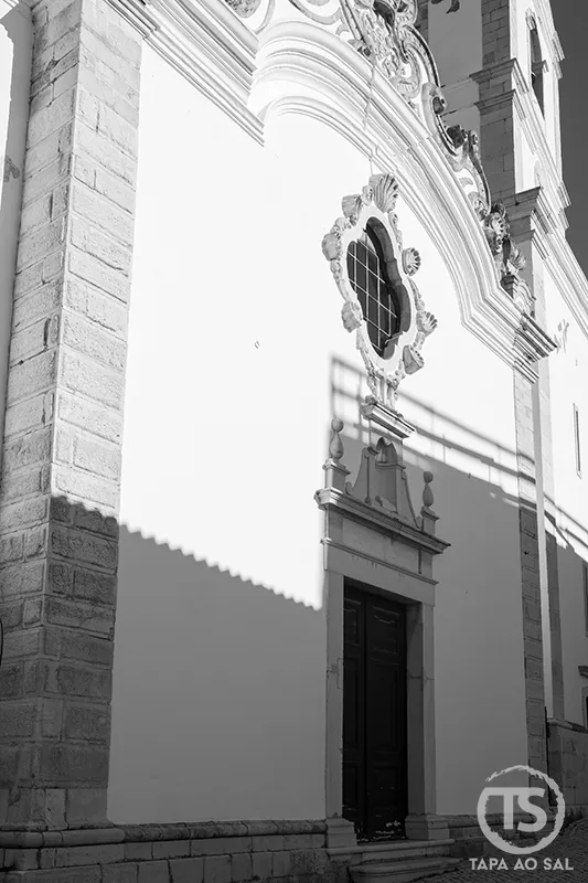 Fachada barroca de igreja no centro histórico de Lagos com portal em pedra e óculo decorado