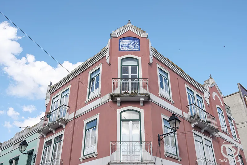 Edifício tradicional no centro de Vila Franca de Xira com fachada rosa e azulejo decorativo